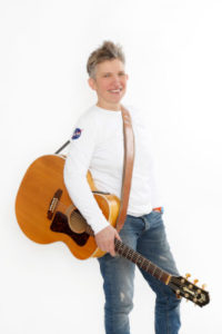 Suli Puschban im Stehen mit umgehängter Gitarre