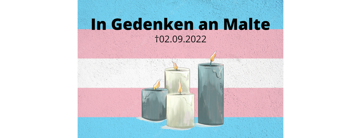 Zu sehen sind vier Kerzen vor einer trans*-Flagge zum Gedenken von Maltes Tod am 2. Sept. 2022